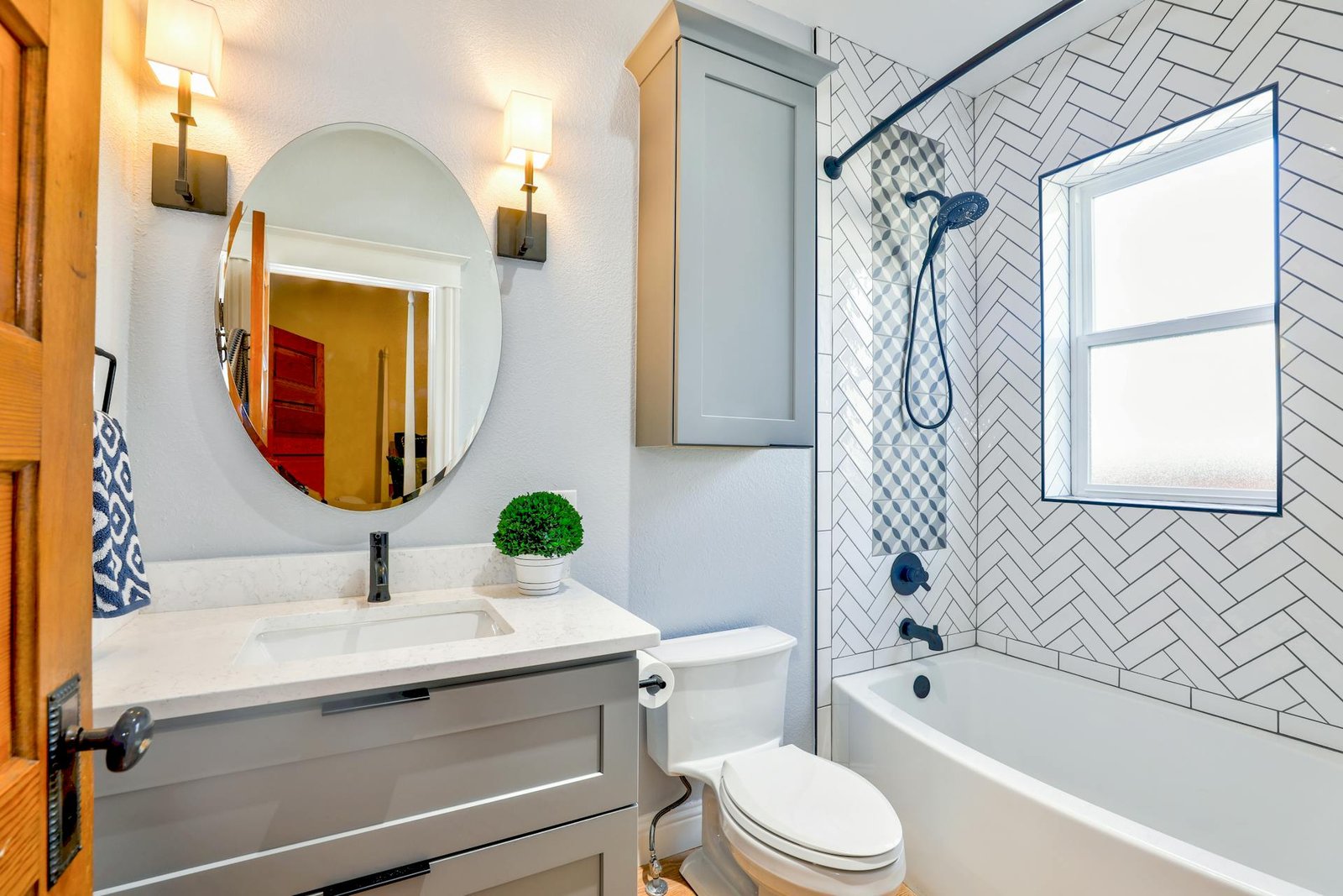 Stylish bathroom with herringbone tile, grey vanity, and oval mirror lighting.