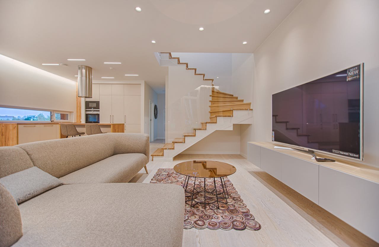 Minimalist living room with floating TV unit and wooden staircase centerpiece.